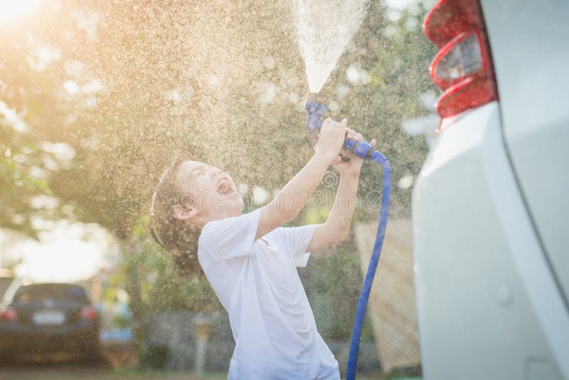 Asian children washing car. Foam, hose.