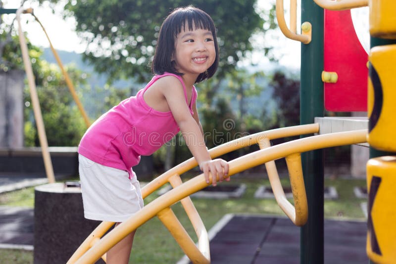 Asian Chinese little girl climbing at playground. Enjoy, outdoor.