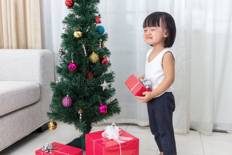Asian Chinese little girl crying beside Christmas tree