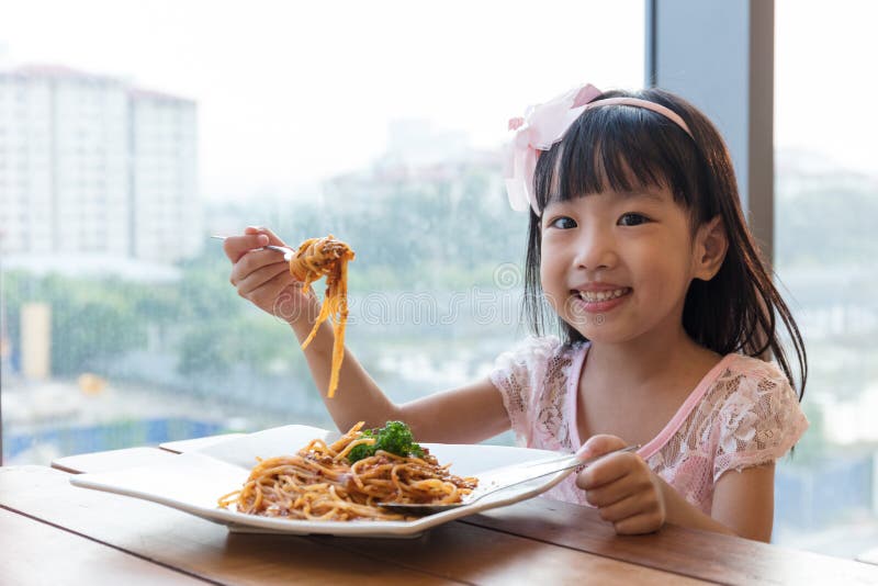 Asian Chinese little girl eating spaghetti bolognese