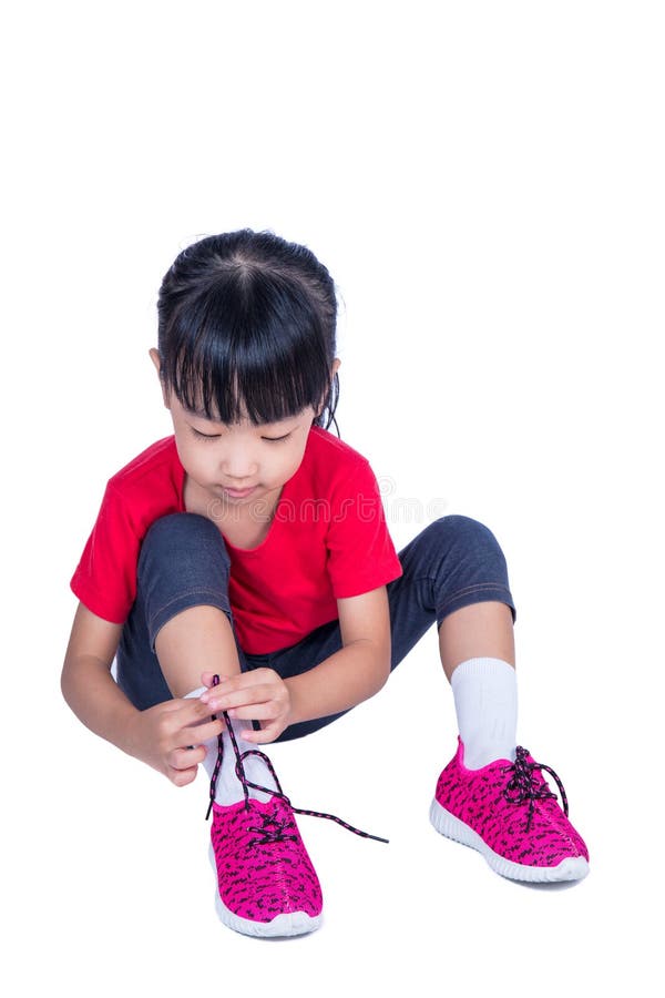 Asian Chinese little girl tying her shoes in isolated white background
