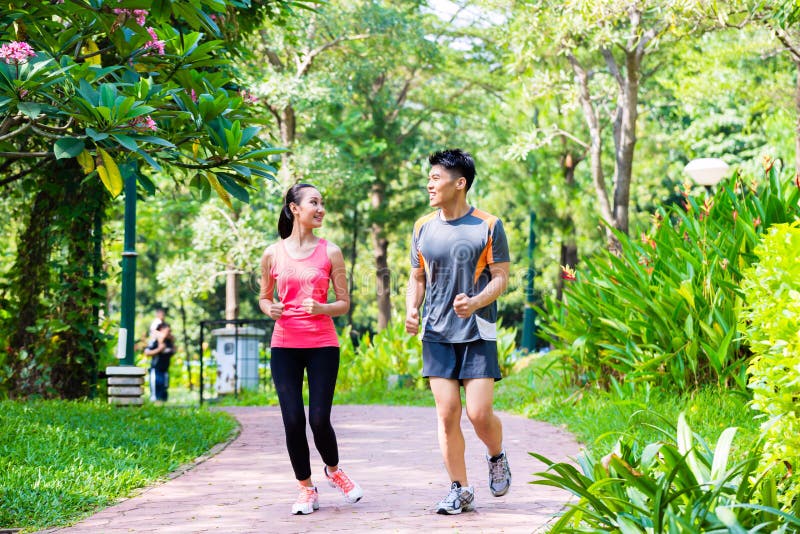 Asian Chinese man and woman jogging in city park stock photo Asian Chinese man and woman jogging in city park stock photo