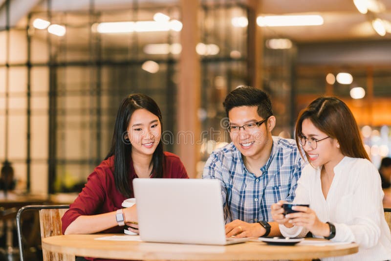 Asian college students group or coworkers using laptop computer together at cafe or university. Casual business, freelance work stock image
