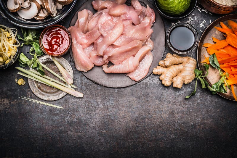Asian cooking preparation with ingredients : chicken Strips, Shoots, vegetables and spices on dark rustic background, top view