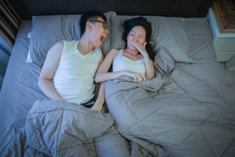 Asian couple with bad breath issues on bed at night