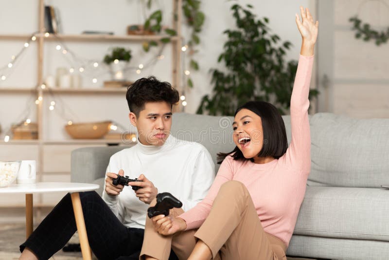 Chinese Girlfriend And Boyfriend Playing Videogame Using Games Console  Sitting On Floor At Home. Computer Gaming And Videogames For Couple, Family  Weekend Leisure Concept Stock Photo, Picture and Royalty Free Image. Image