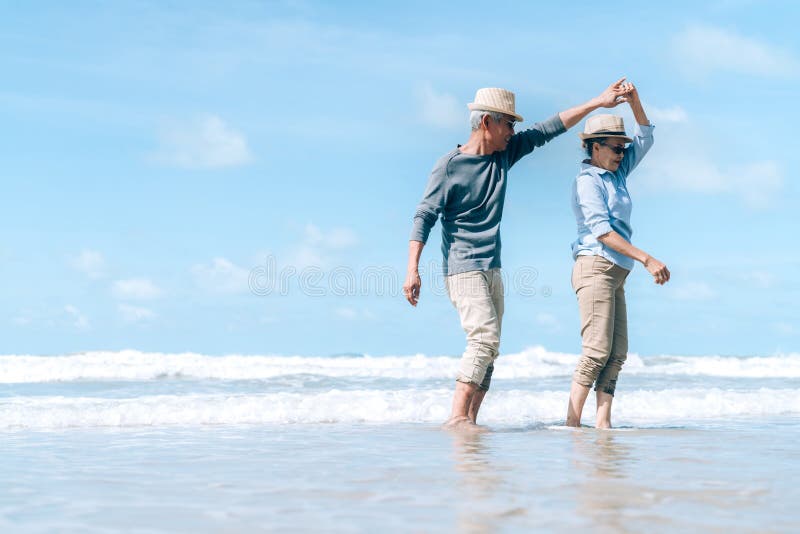 Asian couple senior elder dancing retirement resting relax at sunset beach