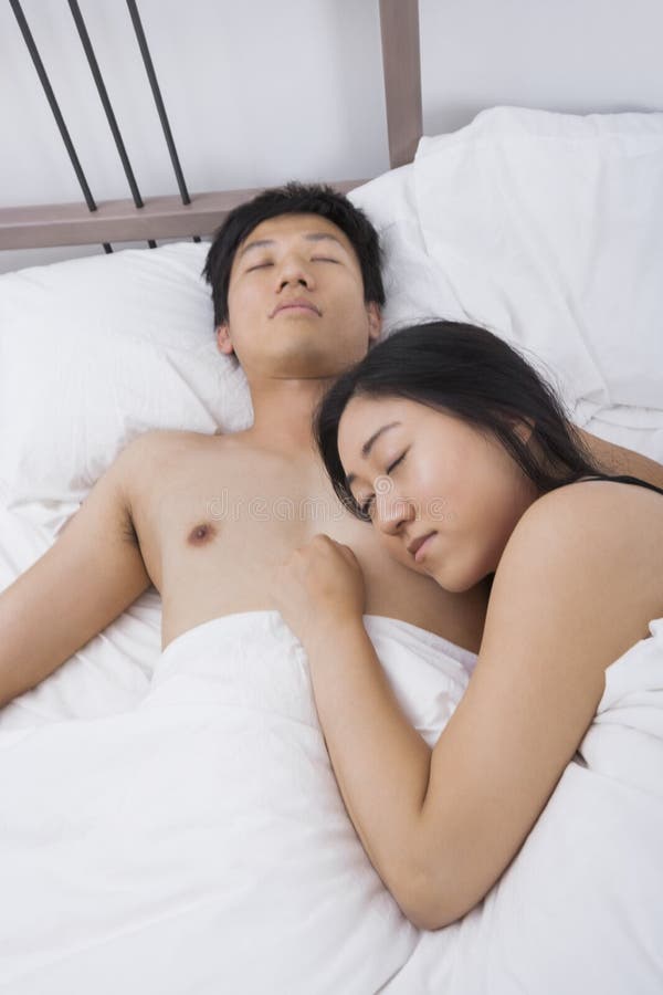 Asian couple sleeping in bed. 