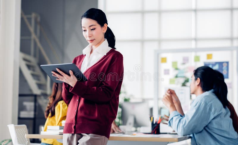 Asian creative director use tablet planning work while ux developer and ui designer brainstorm about mobile app interface design