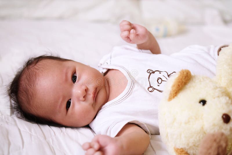 Asian cute baby newborn smile and happy, good mood, on the bed with milk bottle royalty free stock photos Asian cute baby newborn smile and happy, good mood, on the bed with milk bottle royalty free stock photos