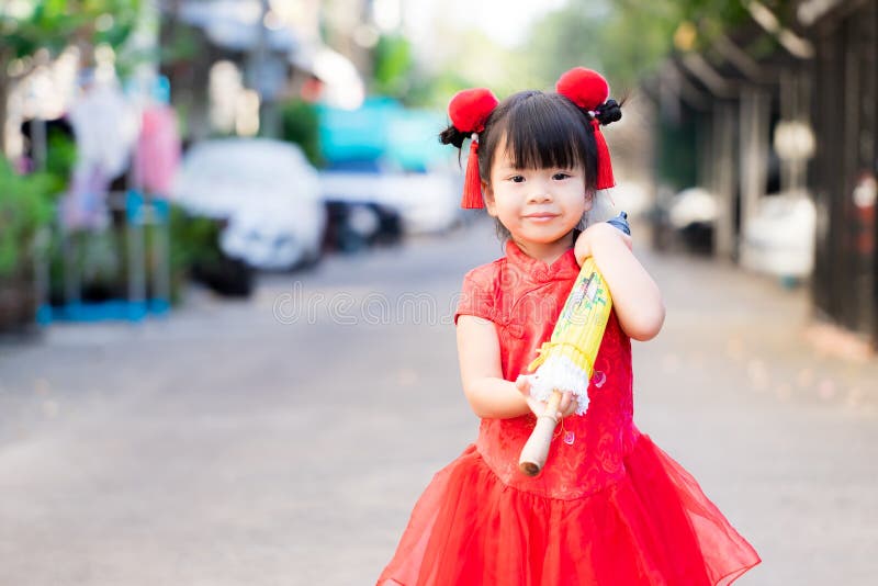 Asian cute girl walking carrying a yellow umbrella  she was wearing a bright red Chinese dress.