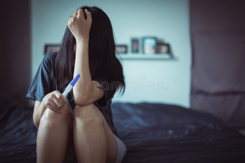 Asian depressed woman sitting in her bedroom after testing pregnancy test
