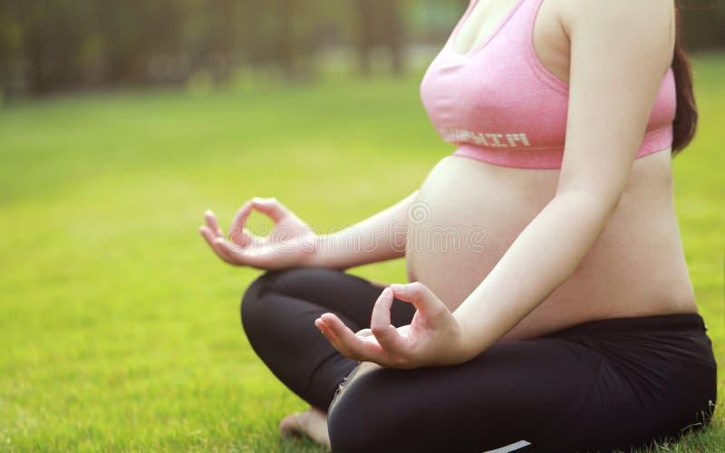 Asian Eastern Chinese young pretty pregnant girl woman do yoga sit in meditation, do lotus gesture of yoga in outdoor nature sun. Asian Eastern Chinese young royalty free stock photography Asian Eastern Chinese young pretty pregnant girl woman do yoga sit in meditation, do lotus gesture of yoga in outdoor nature sun. Asian Eastern Chinese young royalty free stock photography
