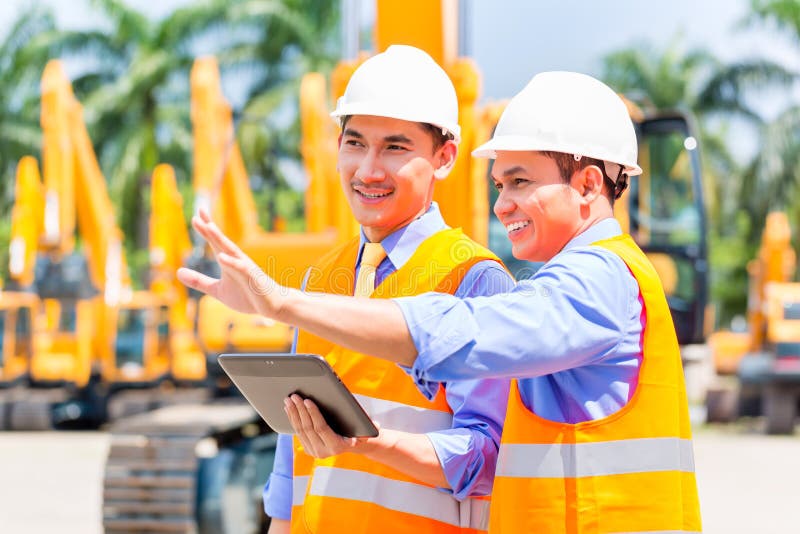 Asian engineer discussing plans on construction site royalty free stock photography