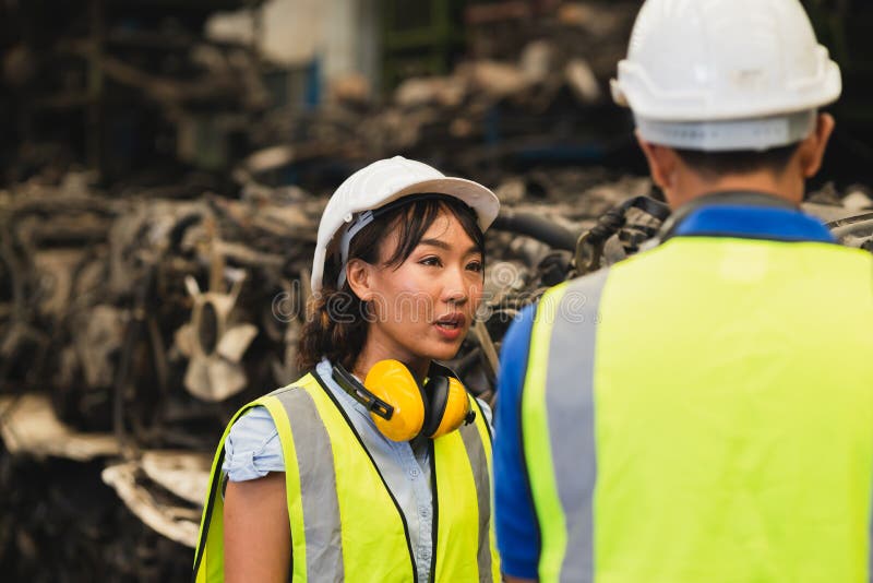 Asian engineer worker working women working together with young male man at heavy industry workplace waring helmet safety suit royalty free stock image