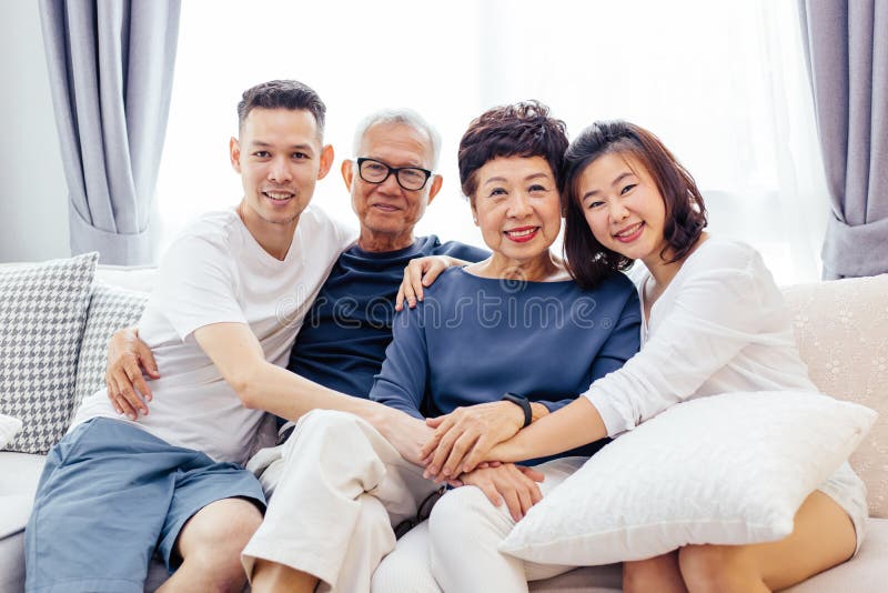 Asian family with adult children and senior parents relaxing on a sofa at home together. royalty free stock photos Asian family with adult children and senior parents relaxing on a sofa at home together. royalty free stock photos