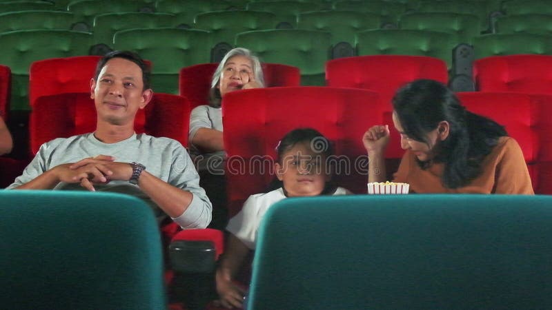 An Asian family audience enjoys watching cinema together at movie theaters.