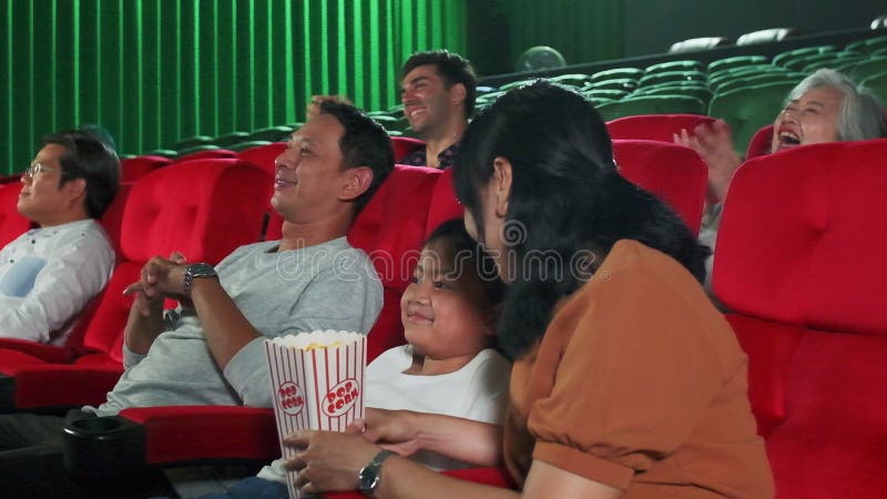 An Asian family audience enjoys watching cinema together at movie theaters.