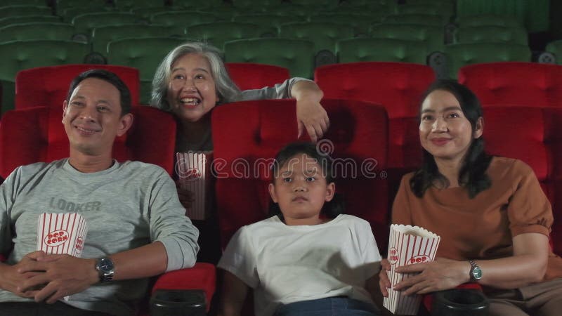 An Asian family audience enjoys watching cinema together at movie theaters.