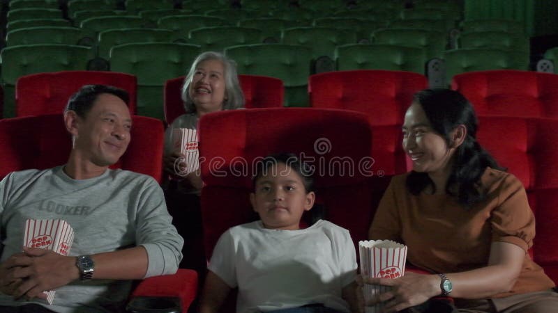 An Asian family audience enjoys watching cinema together at movie theaters.