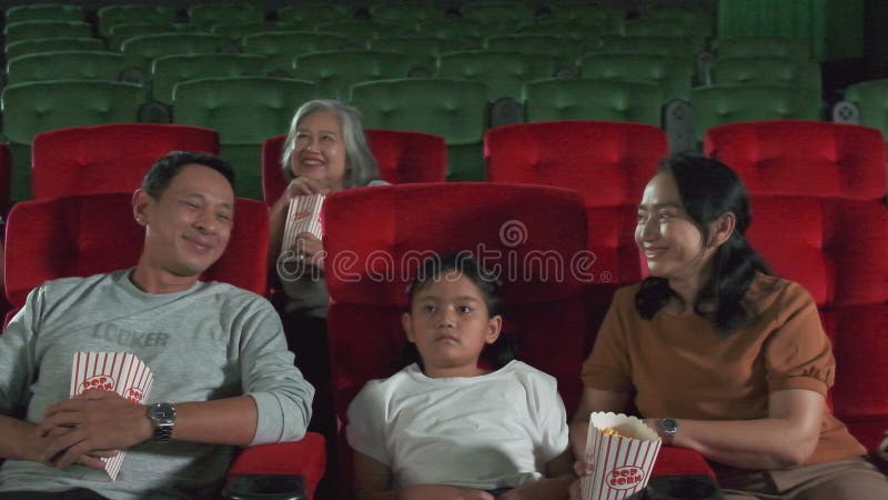 An Asian family audience enjoys watching cinema together at movie theaters.