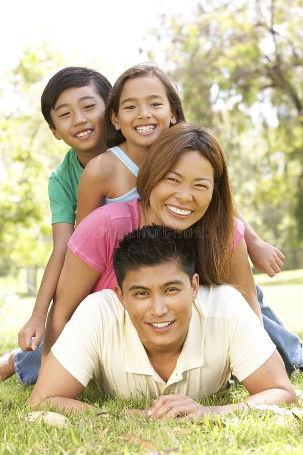 Asian Family Enjoying Day In Park, In A Pile Up Smiling