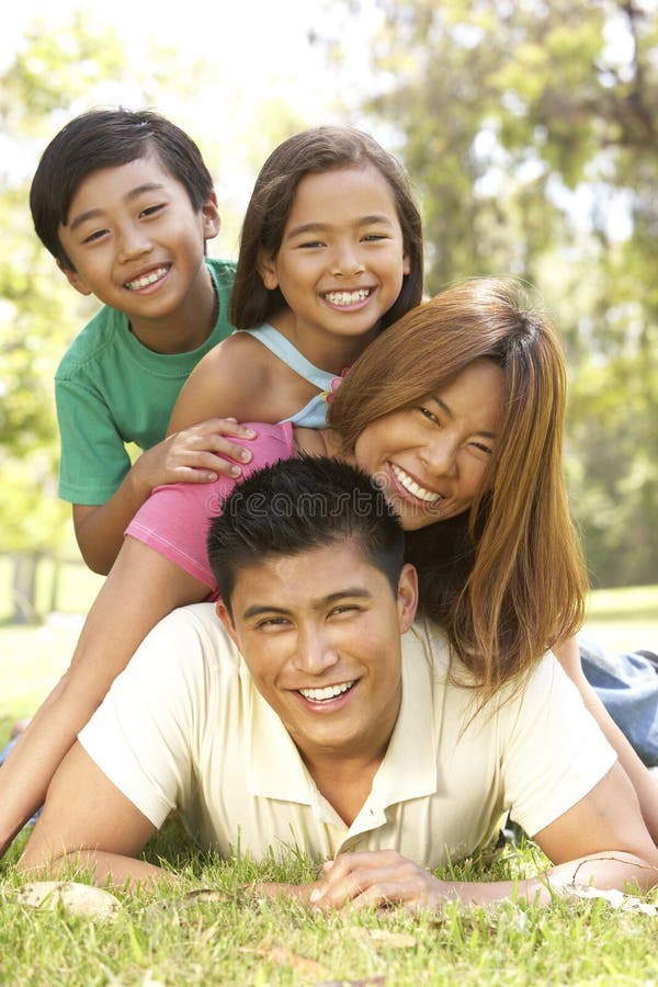 Asian Family Enjoying Day In Park, In A Pile Up Smiling