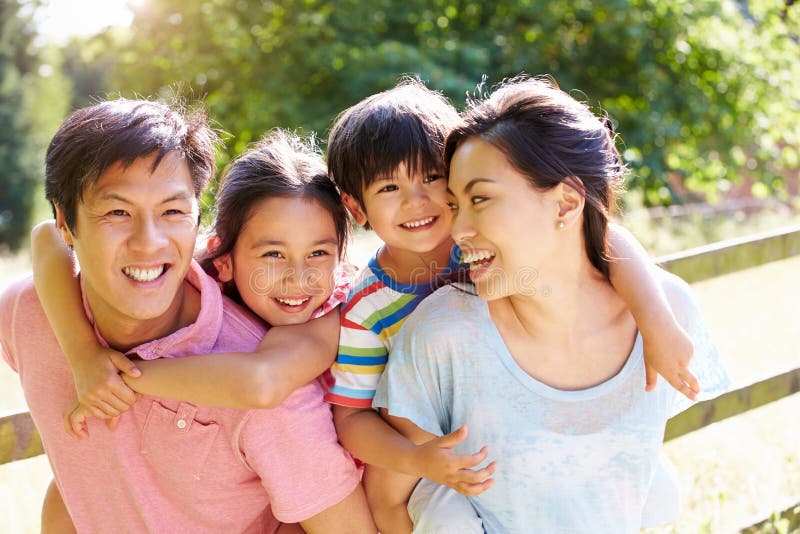 Happy Asian Family Enjoying Walk In Summer Countryside Smiling