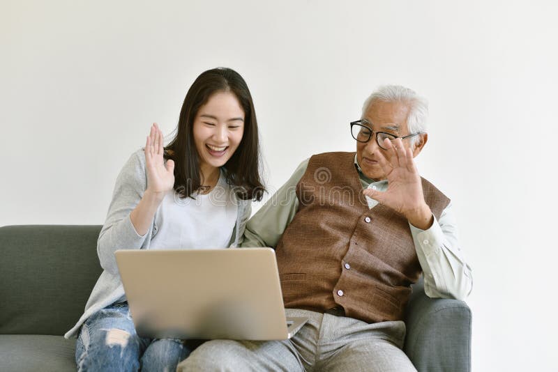 Asian family relationship, Daughter and elderly father using laptop computer talking to another. royalty free stock photos