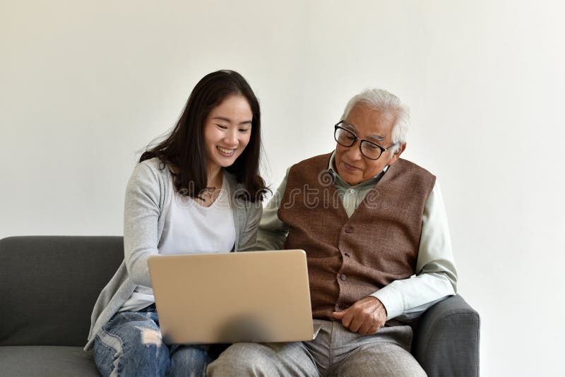Asian family relationship, Daughter and elderly father using laptop computer together. royalty free stock photography