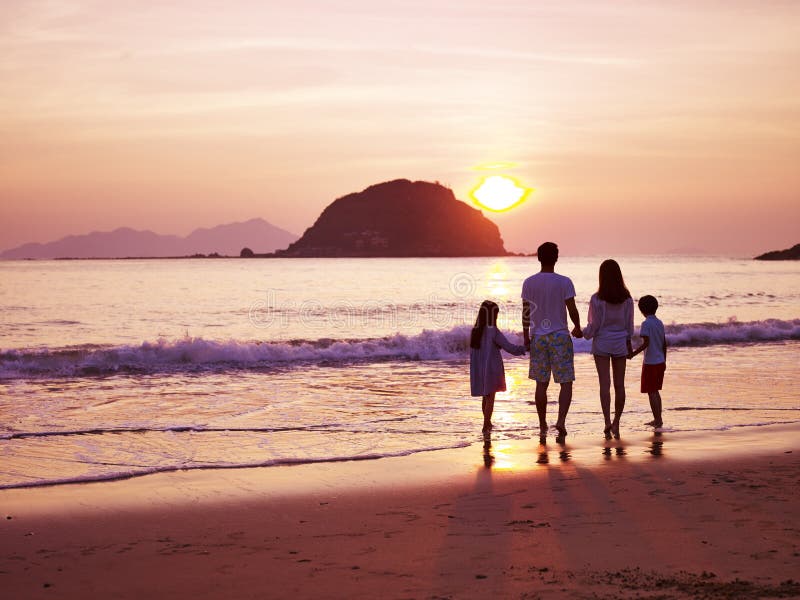 Asian family watching sunrise on beach