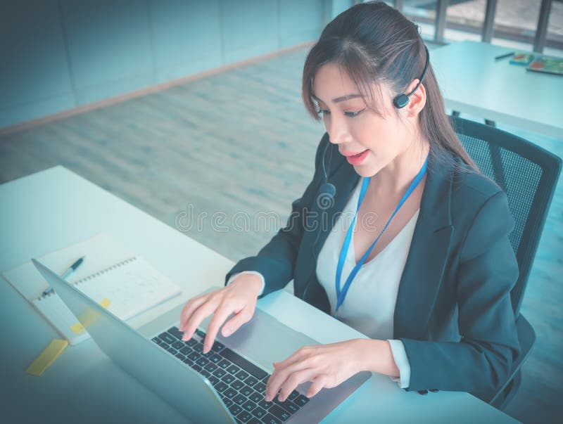 Female customer service is answering call on headphone in an operator service office royalty free stock image