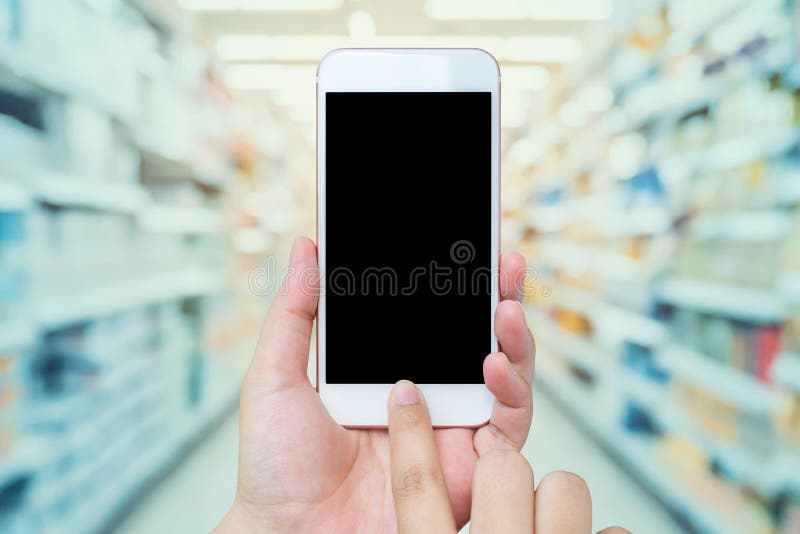 Female hand holding mobile phone with Supermarket background royalty free stock photos Female hand holding mobile phone with Supermarket background royalty free stock photos