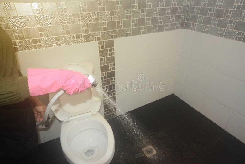 Asian female maid or housekeeper cleaning spray water on floor.