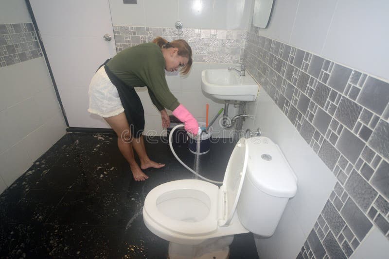 Asian female maid or housekeeper cleaning spray water on floor.