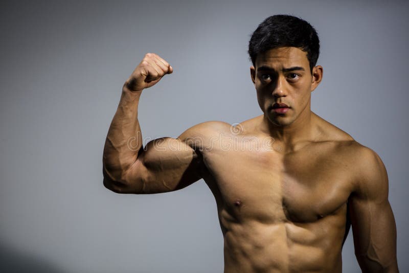 An Asian fitness model flexing his bicep muscle. Front facing. An Asian fitness model flexing his bicep muscle. Front facing.