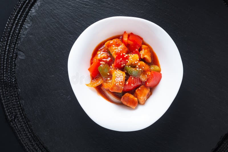 Asian food concept sweet and sour Chicken in white ceramic dish on black slate stone background