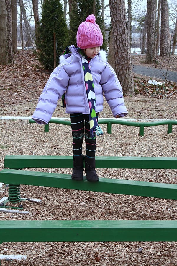 Asian girl bundled for cold walking on beam