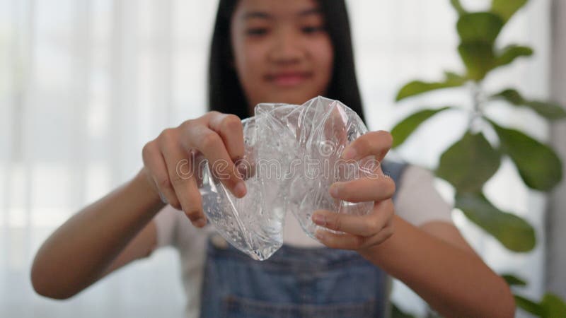 Asian girl crumples plastic water bottles to recycle royalty free stock images