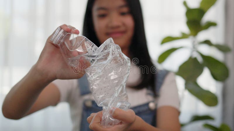 Asian girl crumples plastic water bottles to recycle royalty free stock photo