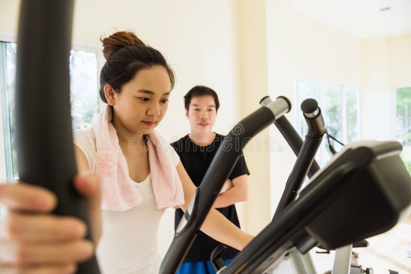 Asian girl exercise in gym with trainer