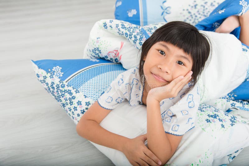 Asian girl lying under a blanket in the bed