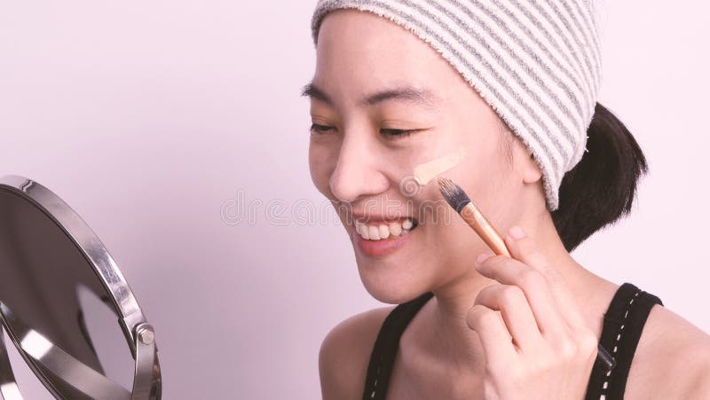 Asian girl making up by foundation liquid real no retouch