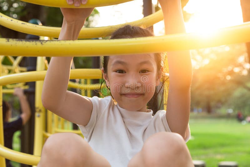 Happy,Asian little girl playing on a playground outdoor and looking at camera in the park,summer,vacation concept stock photo Happy,Asian little girl playing on a playground outdoor and looking at camera in the park,summer,vacation concept stock photo