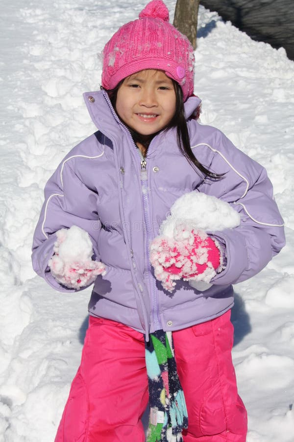 Asian girl playing in snow with chunks