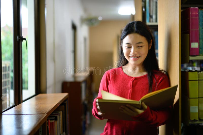 An Asian girl is reading a book in a library stock images