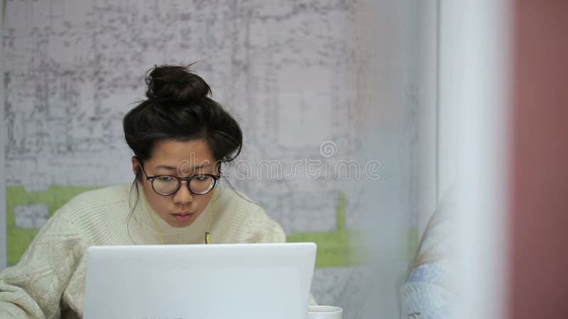 Asian girl student with glasses reading a synopsis on laying urban communications.