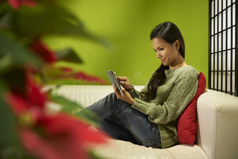 Asian girl with touch pad relaxing on sofa at home royalty free stock images Asian girl with touch pad relaxing on sofa at home royalty free stock images