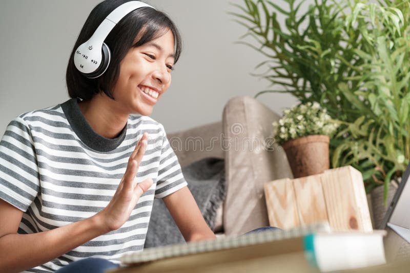 Asian girl waving in greeting online via the internet tutor on tablet, Asia child is study and greeting good morning teacher while. Sitting in living room at royalty free stock image Asian girl waving in greeting online via the internet tutor on tablet, Asia child is study and greeting good morning teacher while. Sitting in living room at royalty free stock image