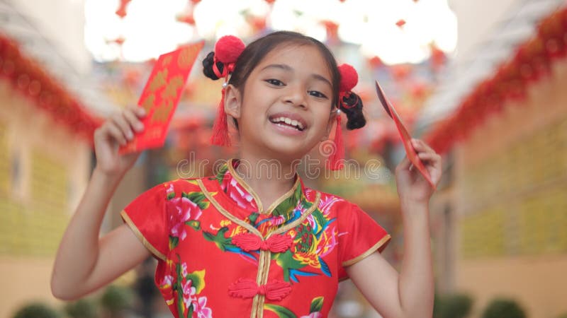 Asian girl wearing red traditional Chinese cheongsam decoration holding red envelopes in hand and lanterns with the Chinese text royalty free stock images